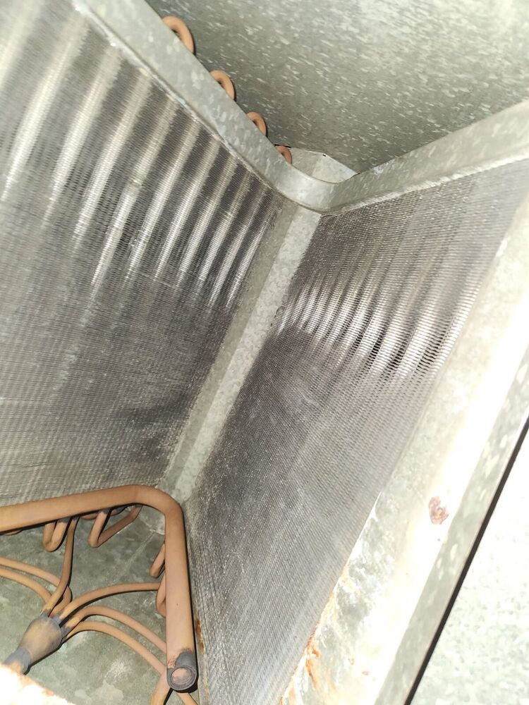 The same evaporator coil after cleaning, with bare metal fins clearly visible