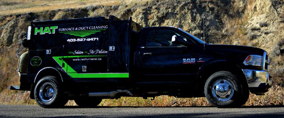 Hat Furnace & Duct Cleaning black vacuum truck parked beside a hillside