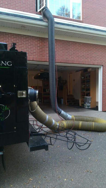 Vacuum hoses running from the truck into a home's garage and up to a second-storey window