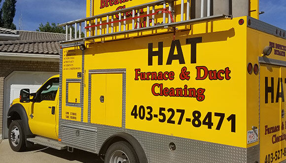 The bright yellow Hat Furnace & Duct Cleaning vacuum truck