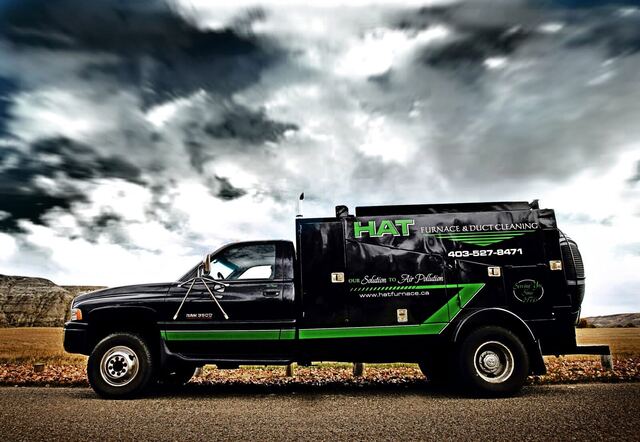 Stylized side profile of the original black HAT Furnace vacuum truck under a moody dramatic sky