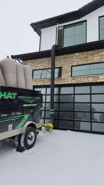 Vacuum hose running from the truck up to the second storey of a stone-faced home