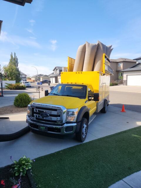 The yellow vacuum truck in a residential driveway with filter bags inflated