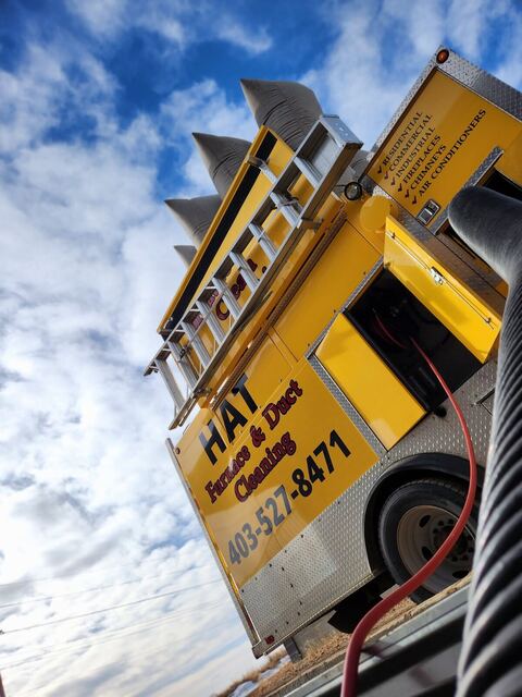 Looking up at the yellow truck against a big cloudy sky, ladder and filter bags visible