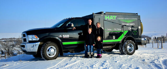 The Huxted family with their black vacuum truck in winter