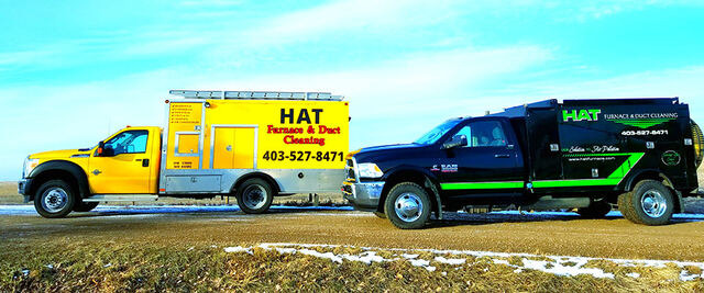 The yellow and black Hat Furnace vacuum trucks parked side by side